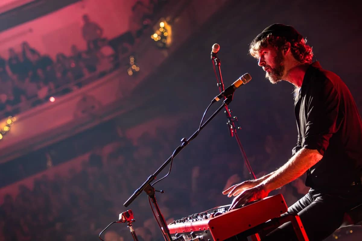 Toetsenist bespeelt zijn rode Nord keyboard voor een vol theater, warm rood en roze licht op de achtergrond